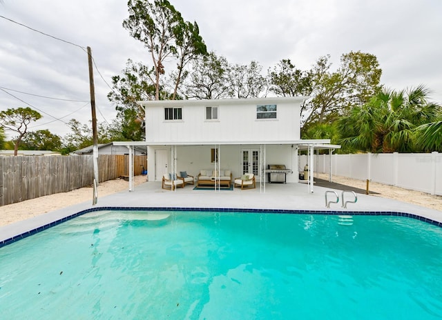 view of swimming pool with an outdoor living space, french doors, a fenced in pool, and a fenced backyard