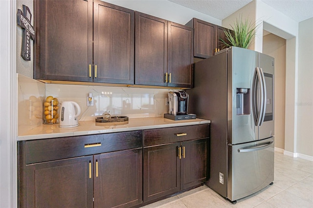 kitchen with a textured ceiling, dark brown cabinetry, decorative backsplash, stainless steel fridge with ice dispenser, and light tile patterned floors