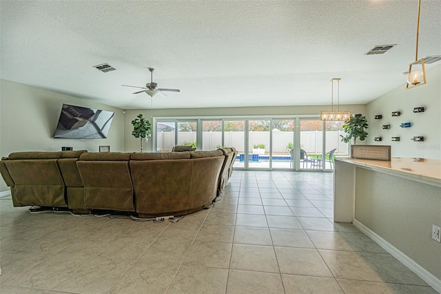 living room with light tile patterned flooring, ceiling fan with notable chandelier, and a textured ceiling