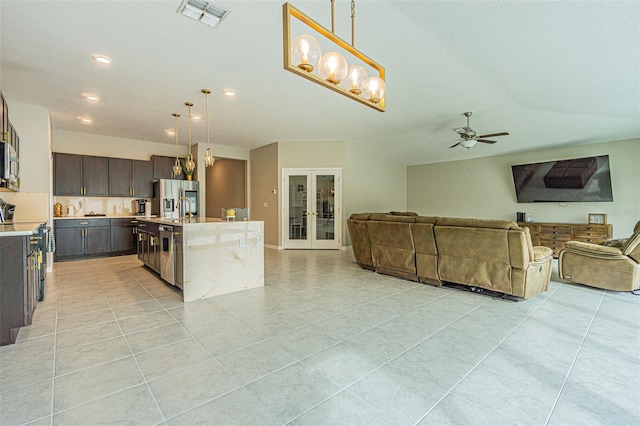 kitchen with dark brown cabinetry, hanging light fixtures, appliances with stainless steel finishes, an island with sink, and french doors