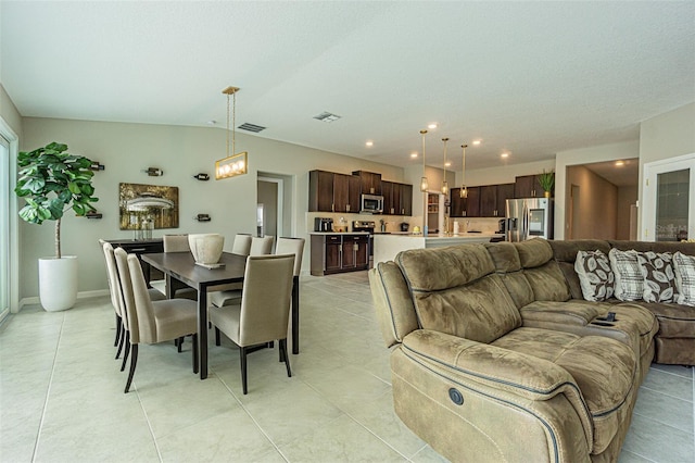 dining space with lofted ceiling, light tile patterned floors, and an inviting chandelier