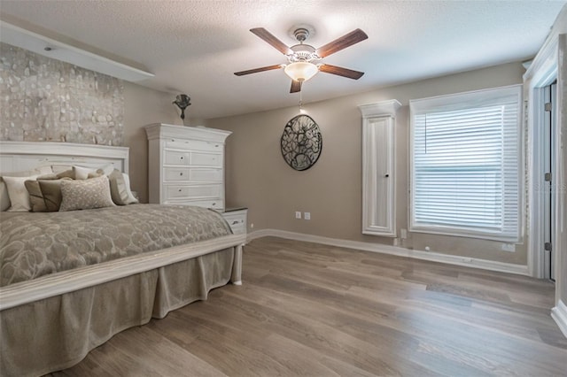 bedroom featuring a textured ceiling, ceiling fan, and light hardwood / wood-style floors