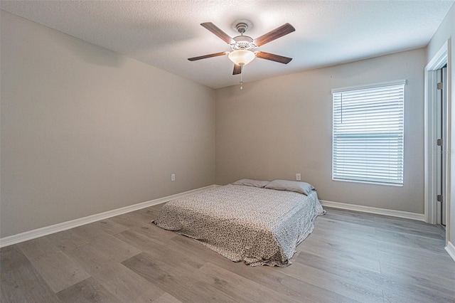 bedroom featuring ceiling fan, wood-type flooring, and a textured ceiling