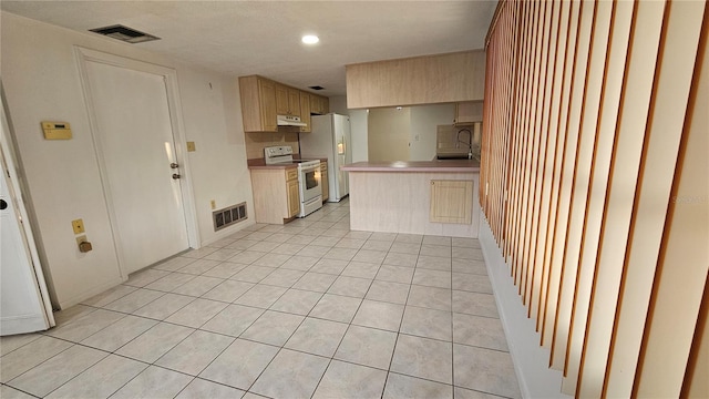 kitchen featuring white appliances, light brown cabinetry, sink, kitchen peninsula, and light tile patterned floors