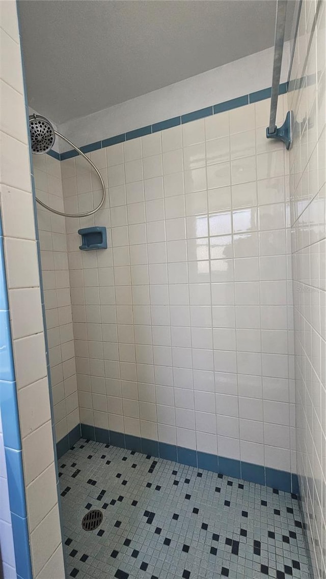 bathroom with tile patterned flooring and a tile shower