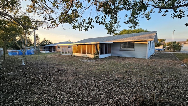 back house at dusk featuring a sunroom