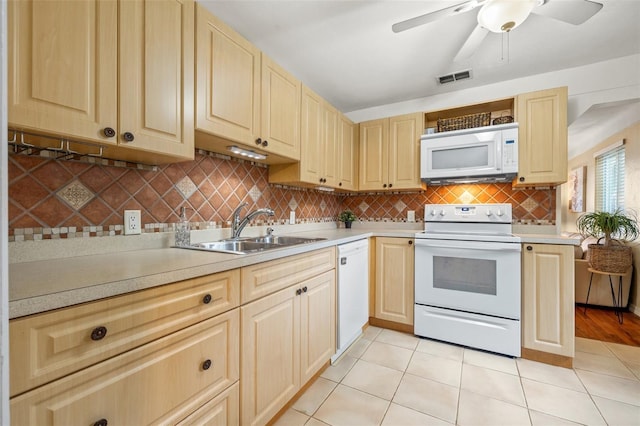 kitchen with light brown cabinetry, light tile patterned floors, sink, and white appliances