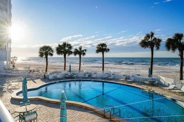 view of pool featuring a view of the beach, a patio area, and a water view