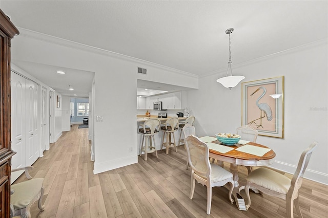 dining area featuring crown molding and light hardwood / wood-style flooring