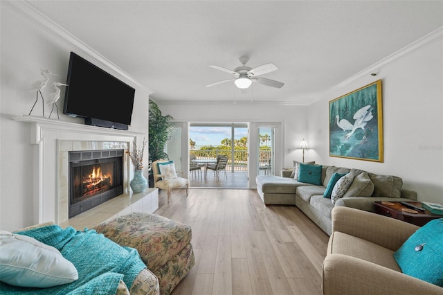 living room with a fireplace, crown molding, light hardwood / wood-style flooring, and ceiling fan