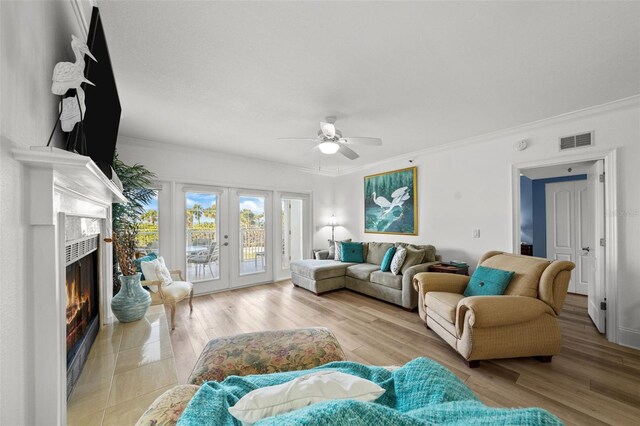 living room featuring crown molding, french doors, ceiling fan, and light wood-type flooring