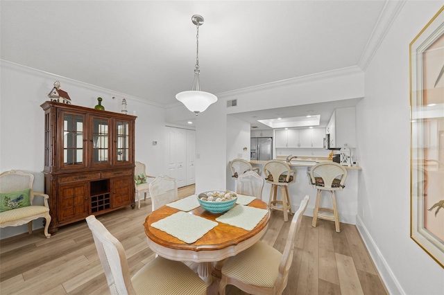 dining area with ornamental molding and light hardwood / wood-style floors