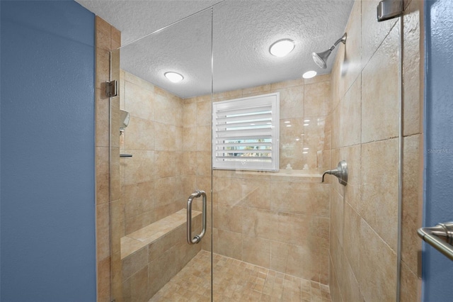 bathroom with a shower with shower door and a textured ceiling