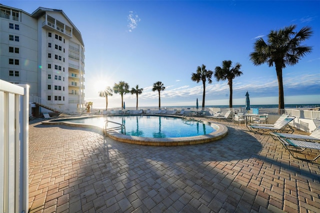 view of pool featuring a water view and a patio area