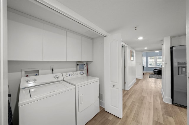 laundry room featuring cabinets, washer and clothes dryer, and light hardwood / wood-style floors