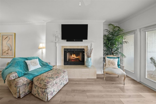 living area with ornamental molding, a healthy amount of sunlight, a fireplace, and light hardwood / wood-style floors