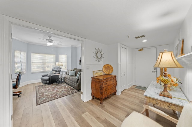 living room featuring crown molding, light hardwood / wood-style floors, and ceiling fan