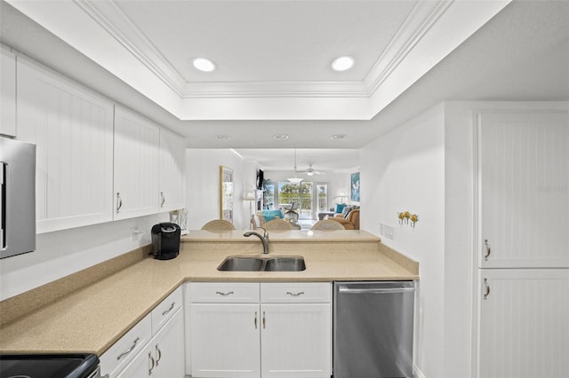 kitchen with sink, white cabinets, ornamental molding, stainless steel dishwasher, and a tray ceiling