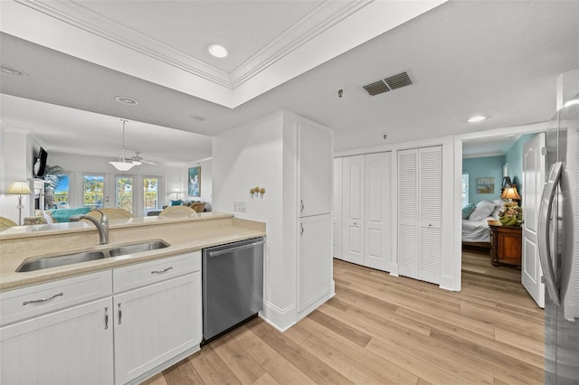 kitchen with appliances with stainless steel finishes, sink, white cabinets, crown molding, and light wood-type flooring