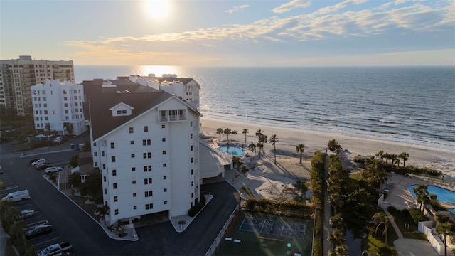 aerial view at dusk featuring a water view and a view of the beach