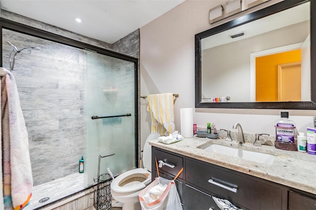 bathroom with vanity, toilet, and a shower with door