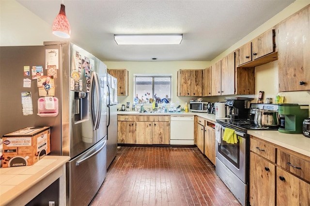 kitchen with pendant lighting, appliances with stainless steel finishes, dark hardwood / wood-style floors, and a textured ceiling