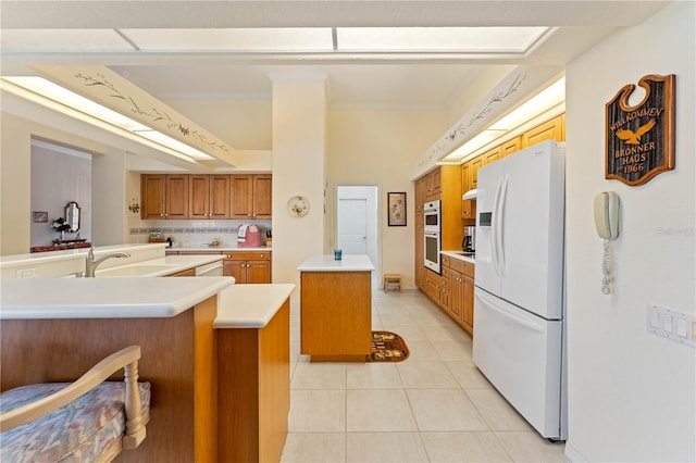 kitchen with sink, a center island, light tile patterned floors, ornamental molding, and white appliances