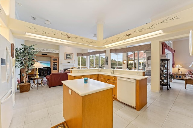 kitchen with sink, light tile patterned floors, kitchen peninsula, a kitchen island, and white appliances