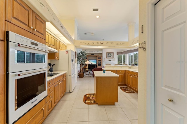 kitchen with ornamental molding, a kitchen island, light tile patterned floors, and white appliances