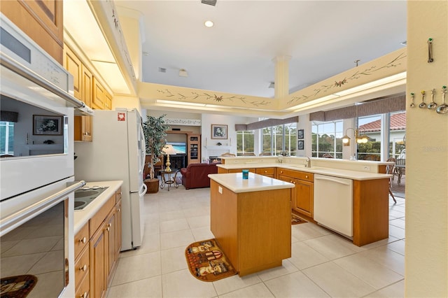 kitchen featuring sink, white appliances, a center island, light tile patterned flooring, and kitchen peninsula