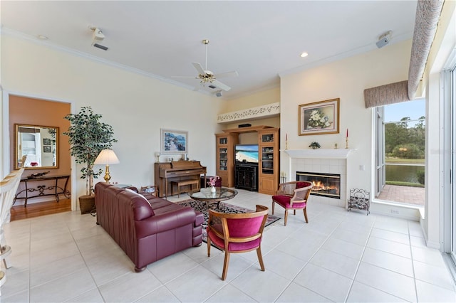 tiled living room with a tile fireplace, ceiling fan, and crown molding