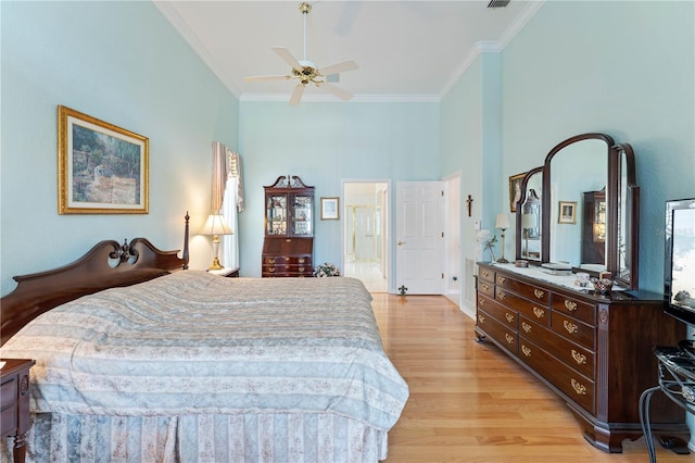 bedroom with ornamental molding, light wood-type flooring, ceiling fan, and ensuite bath