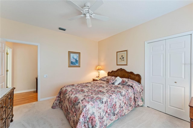 bedroom with ceiling fan, light carpet, and a closet