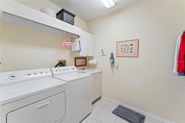 clothes washing area with light tile patterned floors, sink, cabinets, a textured ceiling, and separate washer and dryer