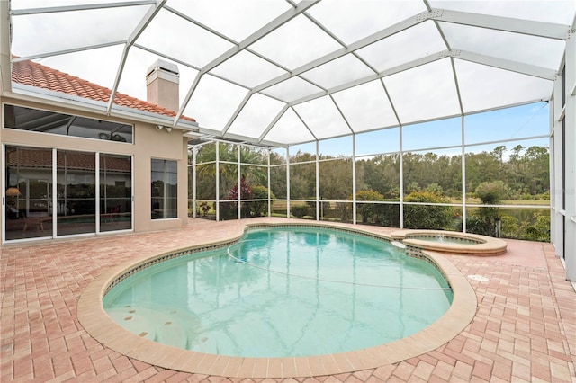 view of swimming pool with an in ground hot tub, a patio, and glass enclosure