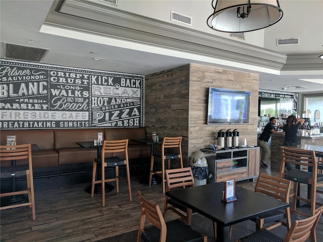 dining area featuring crown molding, wood-type flooring, and a raised ceiling