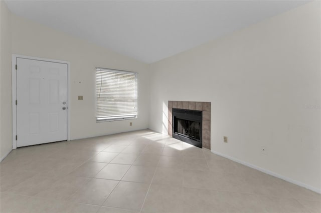 unfurnished living room featuring light tile patterned floors, a tile fireplace, and vaulted ceiling