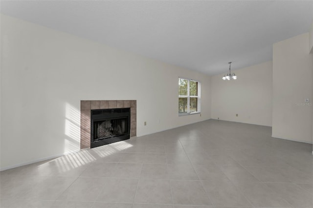 unfurnished living room featuring a chandelier, vaulted ceiling, a tiled fireplace, and light tile patterned flooring