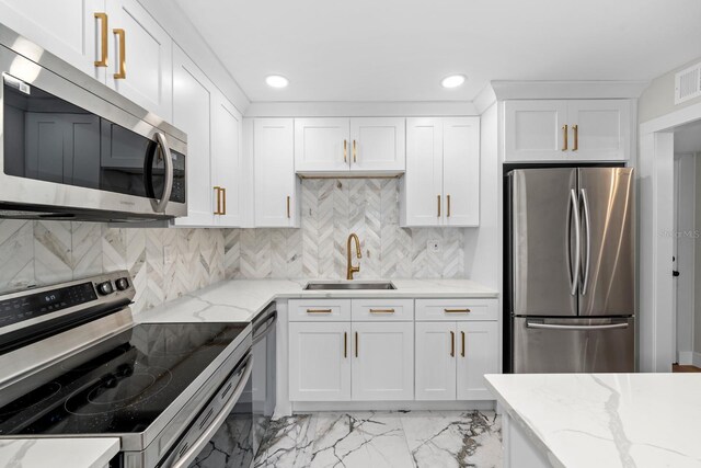 kitchen with white cabinets, decorative backsplash, light stone counters, stainless steel appliances, and a sink