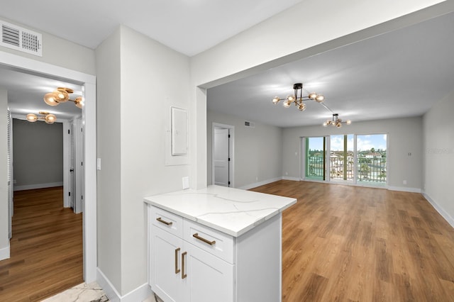 kitchen featuring white cabinetry, baseboards, light wood-style floors, visible vents, and an inviting chandelier