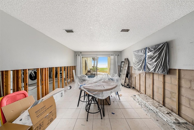 dining room featuring a textured ceiling, light tile patterned floors, and stacked washer / drying machine