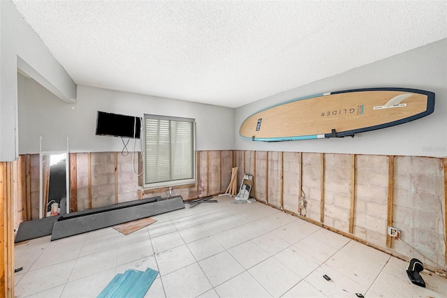 interior space with a textured ceiling and wood walls