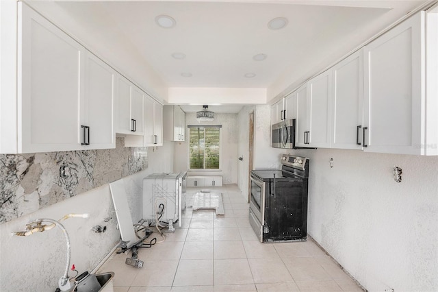 7300 Sunshine Skyway Ln S Unit 108, Saint Petersburg, FL 33711 - kitchen with stainless steel appliances, white cabinets, light tile patterned floors, backsplash, and light countertops
