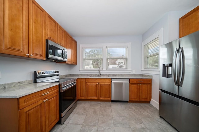 kitchen with light stone countertops, appliances with stainless steel finishes, and sink