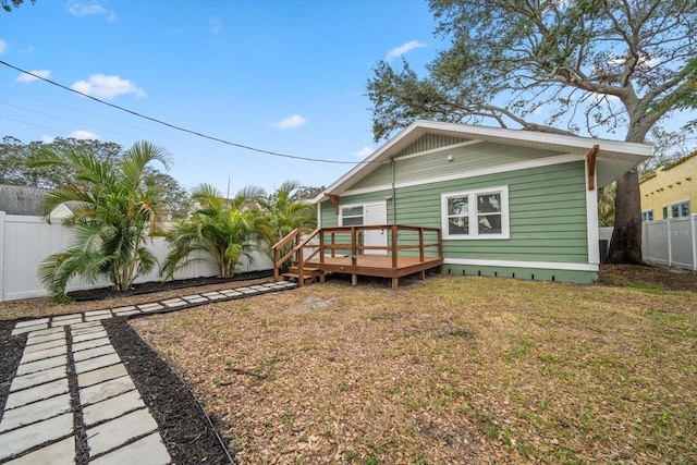 back of house with a deck and a lawn