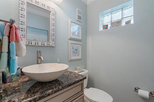 bathroom with toilet, vanity, and ornamental molding