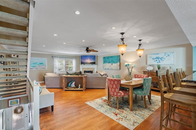 dining space with ceiling fan, a textured ceiling, light hardwood / wood-style flooring, and ornamental molding