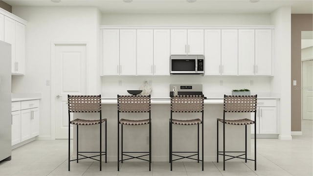 kitchen featuring a kitchen breakfast bar, stainless steel appliances, and white cabinets