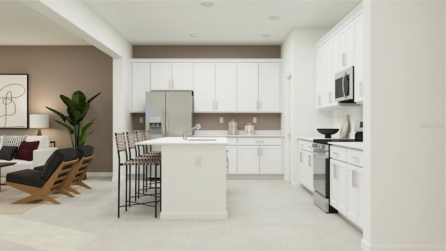 kitchen featuring a kitchen bar, light tile patterned floors, appliances with stainless steel finishes, an island with sink, and white cabinets