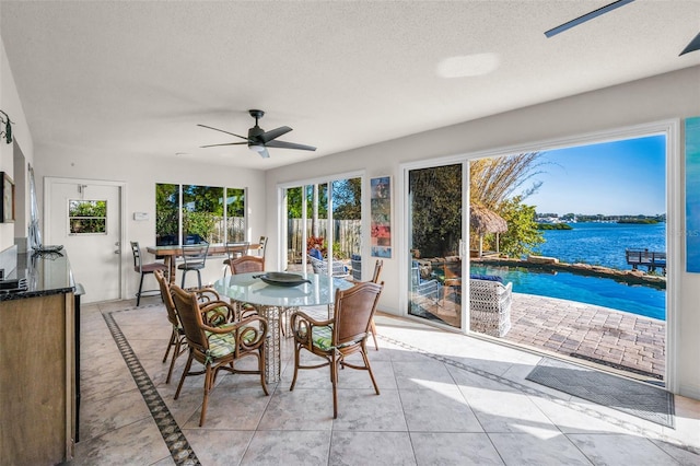 sunroom with a water view, a healthy amount of sunlight, and ceiling fan